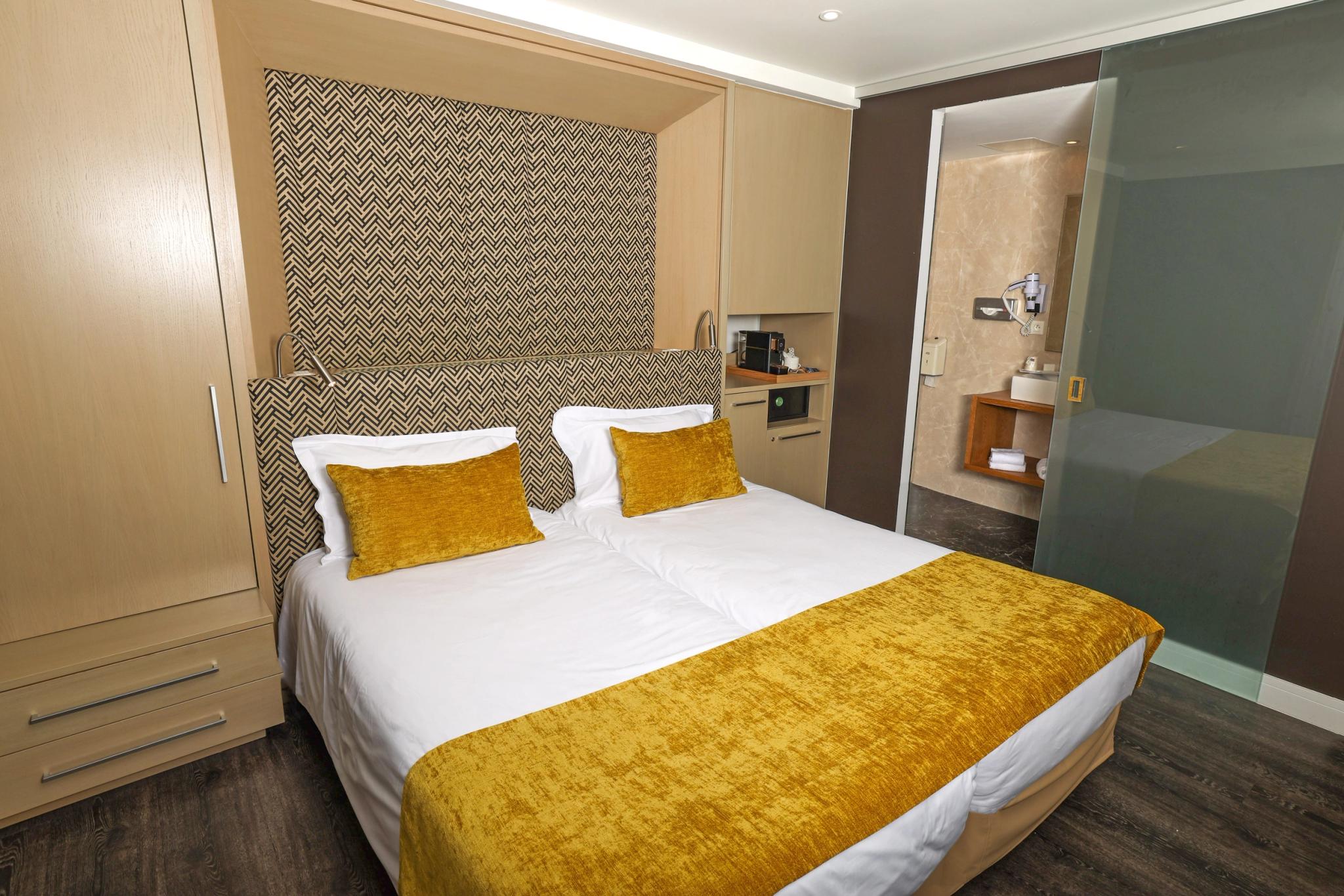 Chambre double avec grand lit et mobilier en bois clair à l’Hôtel Saint-Christophe à Calvi