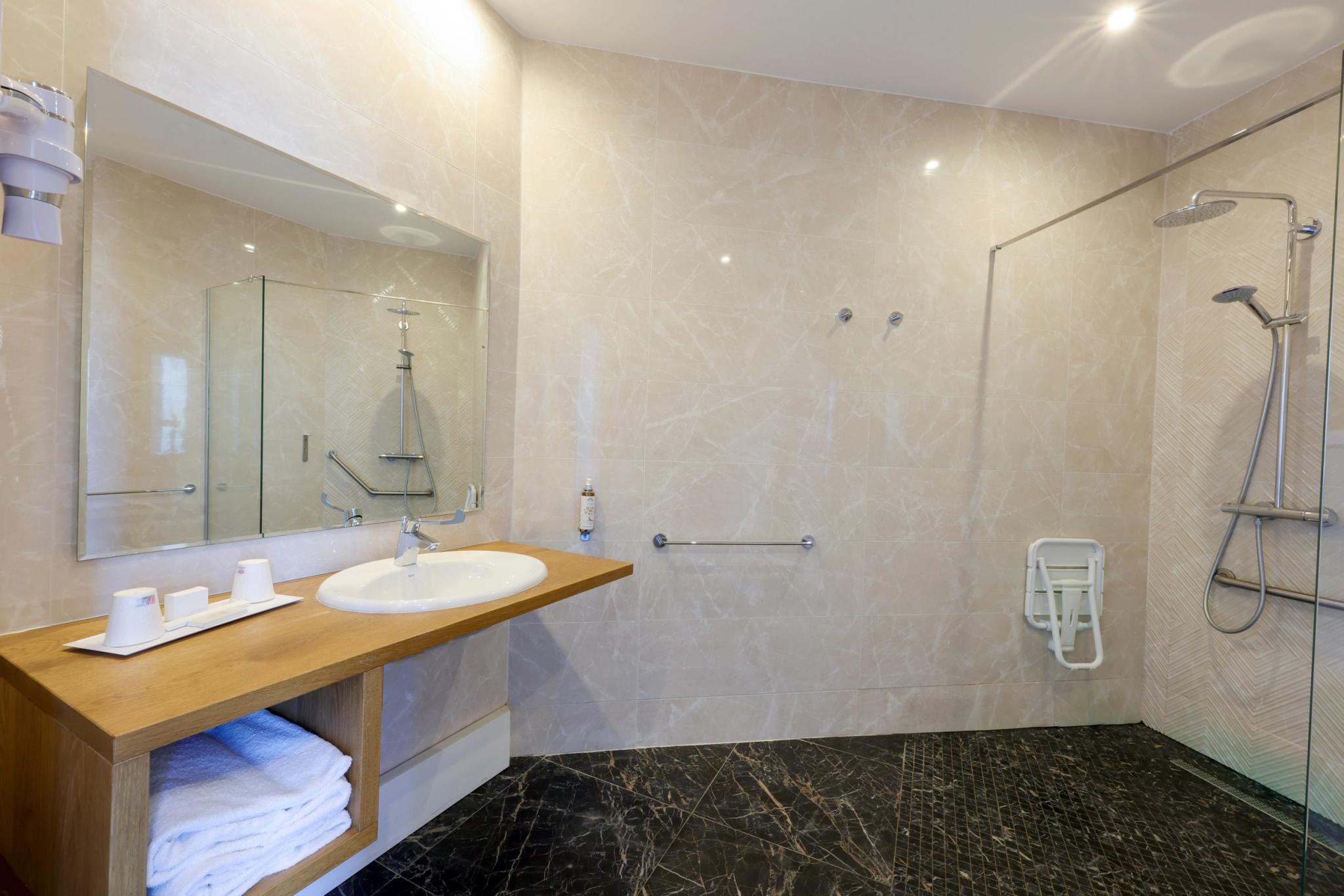 Salle de bain claire avec miroir mural et rangements à l’Hôtel Saint-Christophe en Haute-Corse