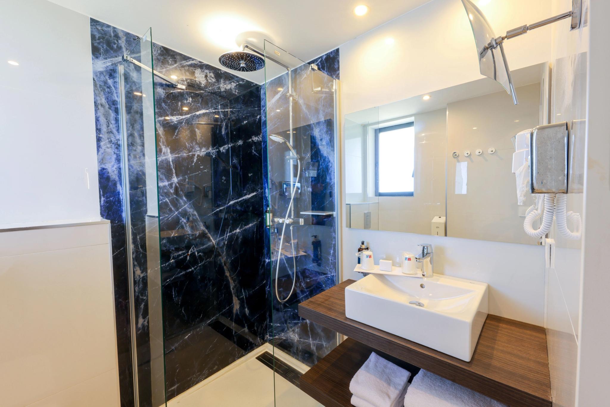 Espace douche confortable dans une salle de bain privative de chambre avec vue mer partielle