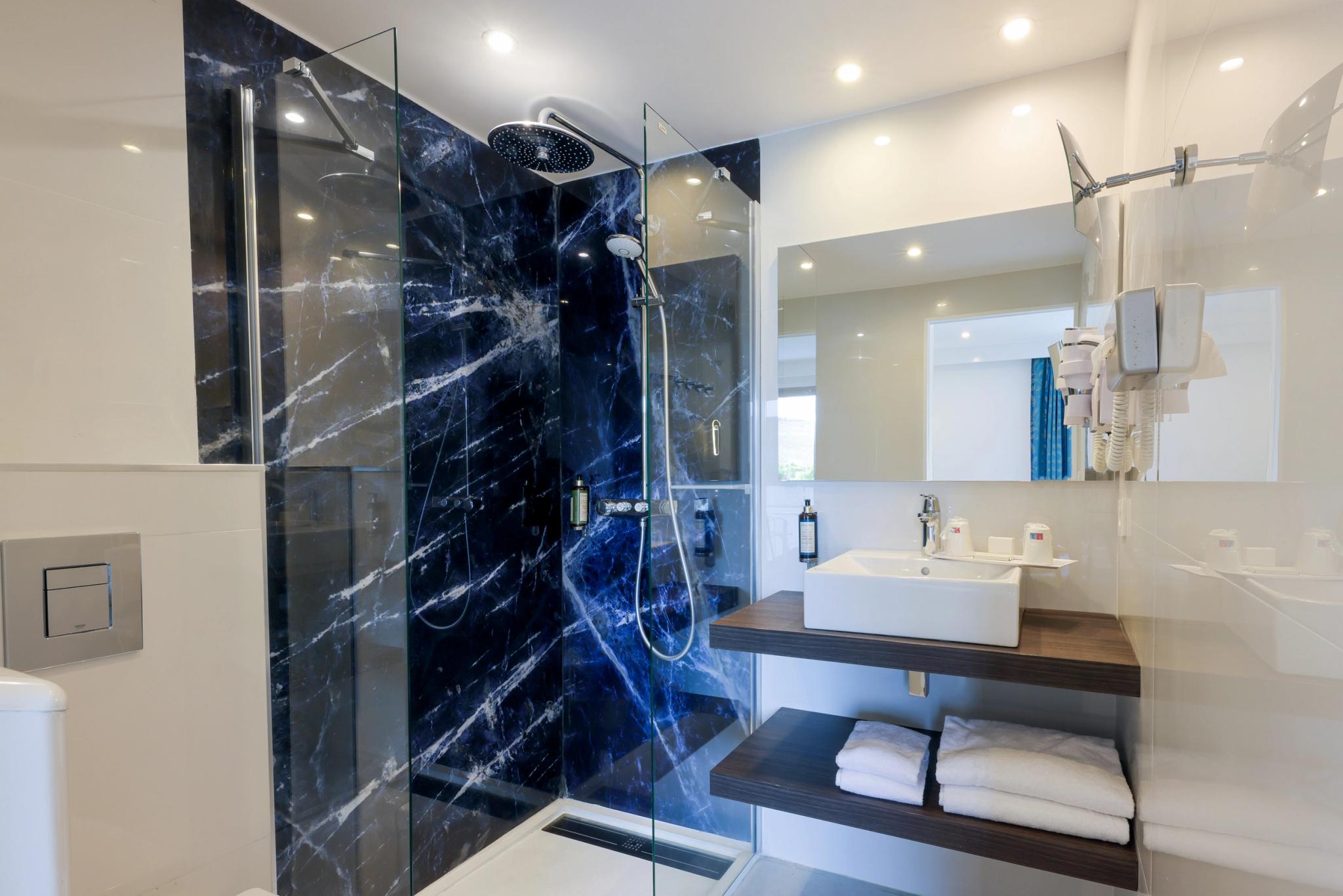 Salle de bain moderne attenante à la chambre avec grande douche à l’italienne