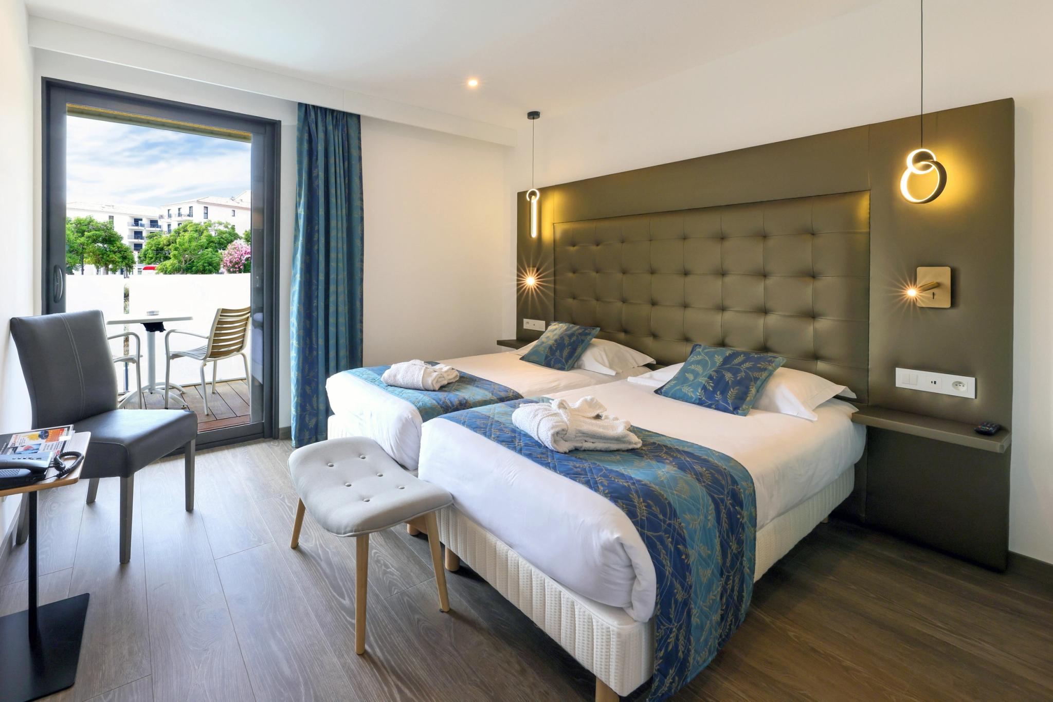 Chambre double lumineuse de l'Hôtel Saint-Christophe à Calvi avec balcon offrant une vue panoramique sur la mer